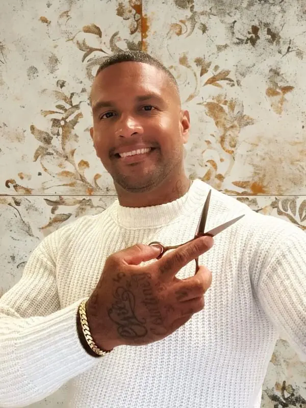 A barber at Palm Beach Hair Co. holding shears, ready for a client